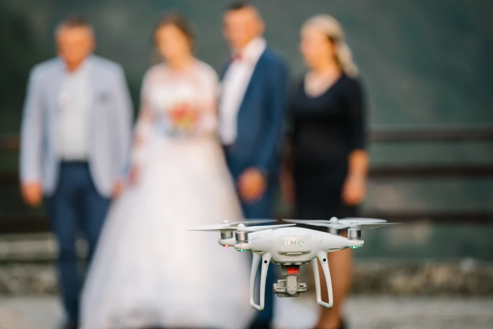 Homme d'affaires souriant en chemise grise boutonnée, posture détendue, appuyé contre une surface, regard confiant dirigé vers la caméra dans un environnement professionnel moderne