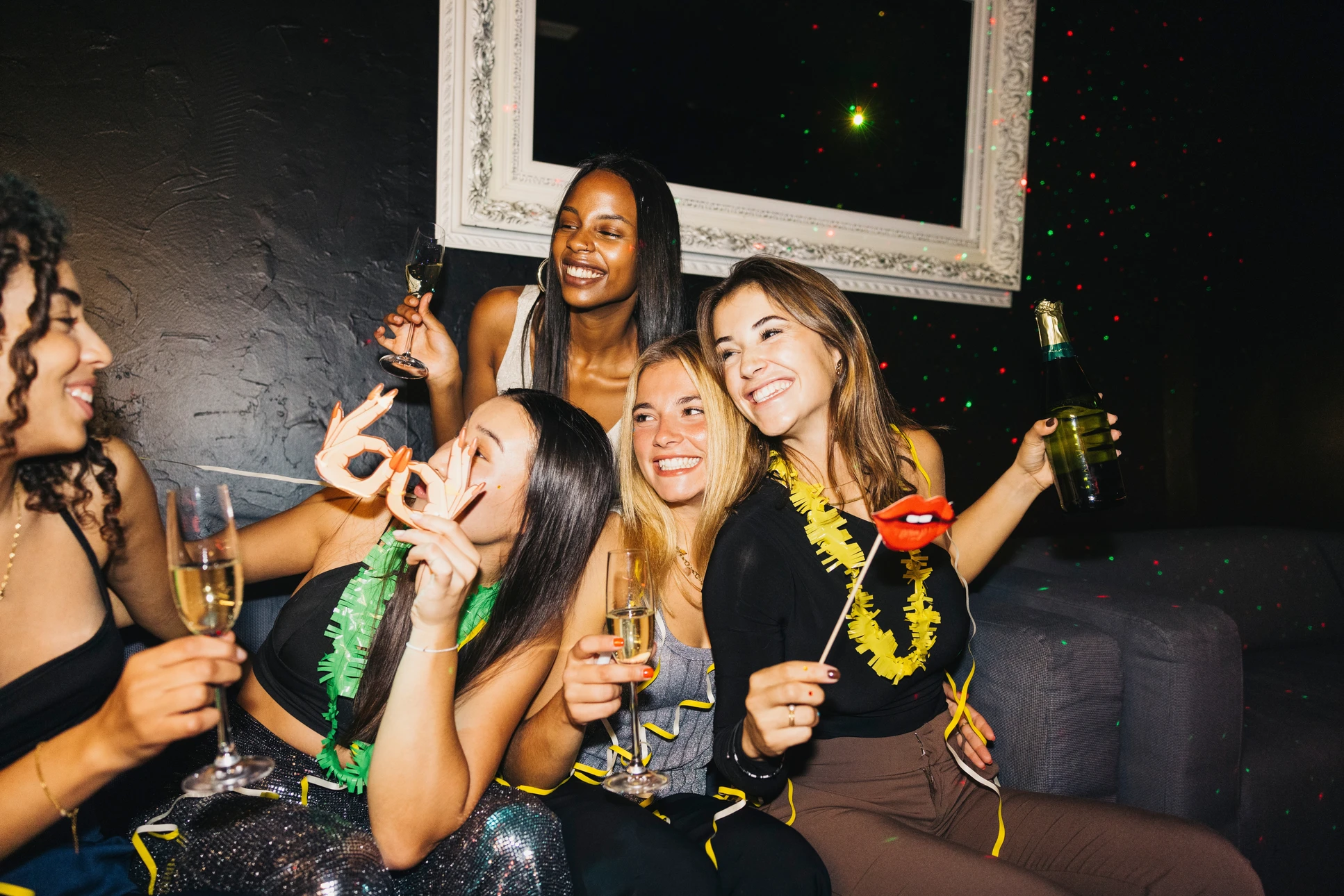 Scène de célébration en intérieur avec plusieurs personnes trinquant avec des flûtes à champagne remplies, confettis ou neige artificielle tombant dans l'air créant une atmosphère festive sur fond noir